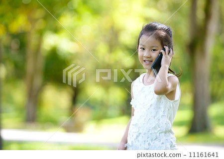 Little girl in casual using mobile smart phone in a park Little girl in casual using mobile smart phone in a park 11161641