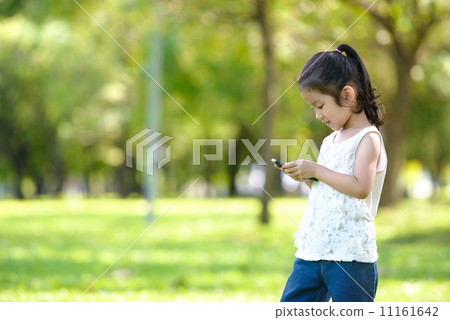 Little girl in casual using mobile smart phone in a park Little girl in casual using mobile smart phone in a park 11161642