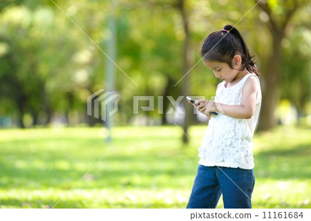 Little girl in causal using mobile smart phone in a park 11161684