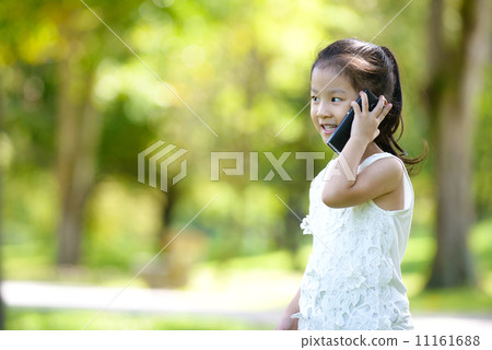 Little girl in causal using mobile smart phone in a park 11161688