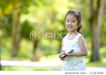 Little girl in causal using mobile smart phone in a park 11161689