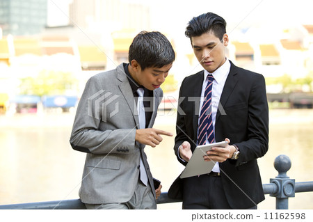 Young business executives looking at tablet in financial hub 11162598