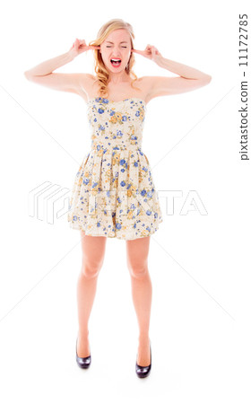 Young woman standing with fingers in her ears Young woman standing with fingers in her ears 11172785