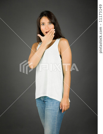 Portrait of a young woman looking shocked with her hands over mouth 11173149