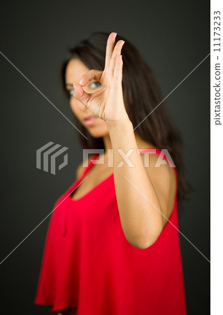 Side profile of a young woman looking through finger's hole 11173233