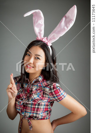 Portrait of sexy asian cowgirl ready for easter fingers crossed 11173645