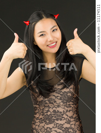 Asian young woman dressed up as an devil with showing thumb up sign with both hands 11174511