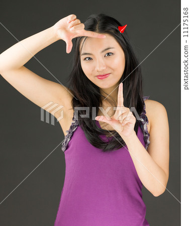 Devil side of a young Asian woman making frame with fingers and smiling Devil side of a young Asian woman making frame with fingers and smiling 11175168