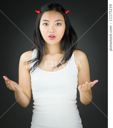 Shocked Asian young woman in devil horns gesturing Shocked Asian young woman in devil horns gesturing 11175239