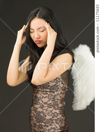 Asian young woman dressed up as an angel suffering from headache 11175685