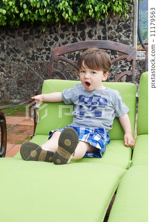 Boy sitting on a lounge chair and yawning Boy sitting on a lounge chair and yawning 11179563