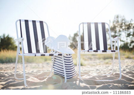 two beach lounges with beach bag and white hat 11186883