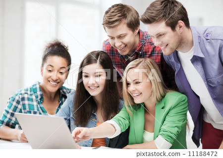 smiling students looking at laptop at school 11188472