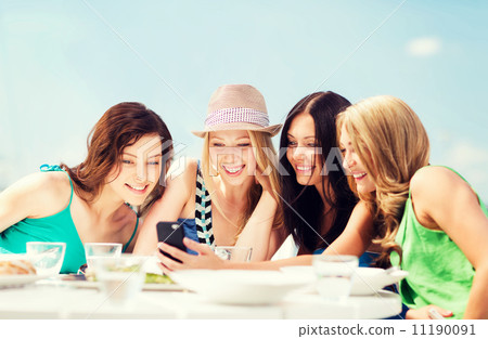 girls looking at smartphone in cafe on the beach girls looking at smartphone in cafe on the beach 11190091