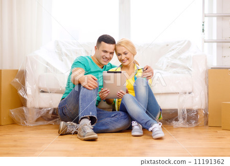 smiling couple with tablet pc in new home 11191362