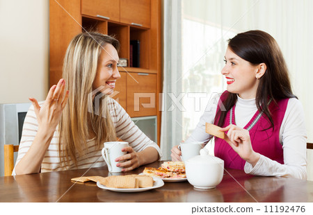 Two young women drinking tea with cookies Two young women drinking tea with cookies 11192476