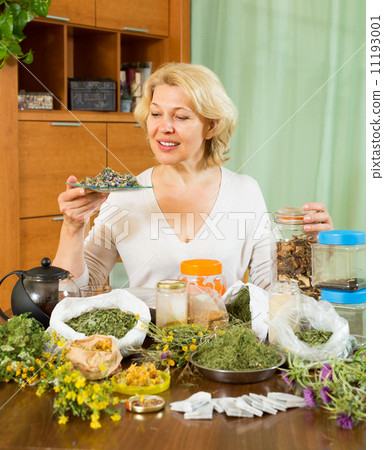 Mature woman with herbs at table 11193001