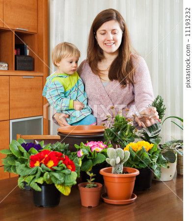 Young mother and baby in the room transplanting potted flowers Young mother and baby in the room transplanting potted flowers 11193232
