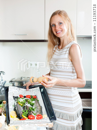 Pregnant housewife cooking trout 11193718