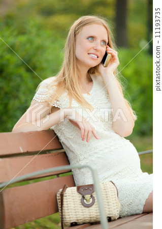 woman sitting on bench and talking by phone 11193735