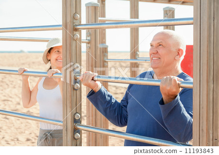 Sporty mature couple training with chin-up bar 11193843