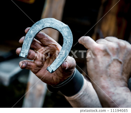 Blacksmith's dirty hands holding horseshoe 11194085