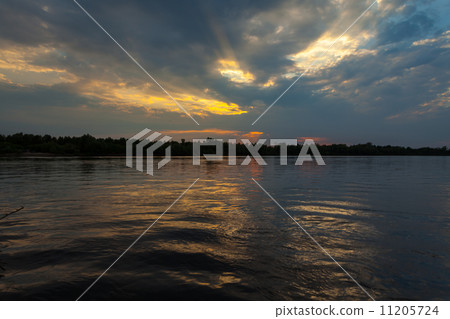 Sunrise over the lake with reflection of bare trees in the water. 11205724