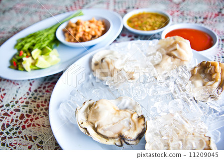 Oysters on ice serving with vegetables in Thai seafood restaurant Oysters on ice serving with vegetables in Thai seafood restaurant 11209045