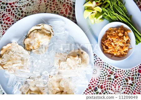 Oysters on ice serving with vegetables in Thai seafood restaurant Oysters on ice serving with vegetables in Thai seafood restaurant 11209049
