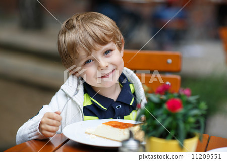 Little boy eating cake in outdoor cafe. Little boy eating cake in outdoor cafe. 11209551