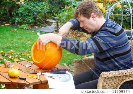 Young man making halloween pumpkin 11209574