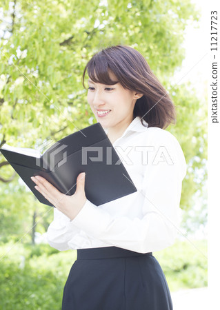 觀看筆記本的女商人在公園 觀看筆記本的女商人在公園 11217723