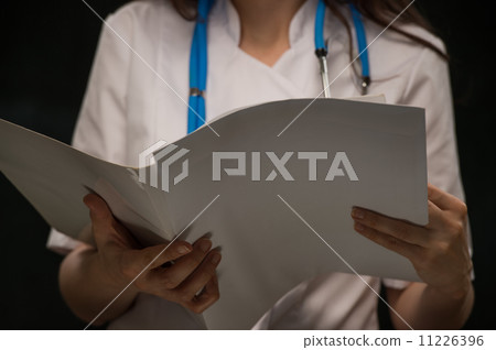 Unrecognizable doctor reading medical record 11226396