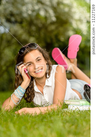 Cheerful student girl lying grass calling phone 11227169
