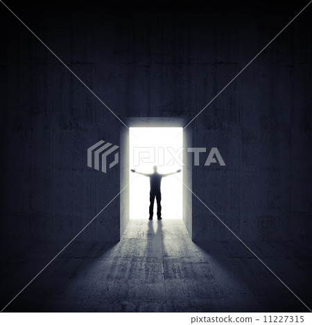 Abstract dark concrete interior with glowing door and man silhou 11227315