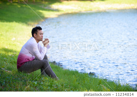 Young man in causal alone in thoughts near the edge of the waters Young man in causal alone in thoughts near the edge of the waters 11234814