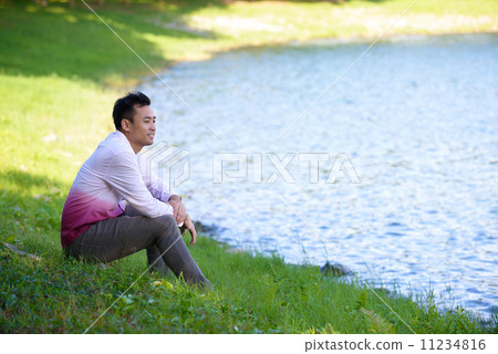 Young man in causal alone in thoughts near the edge of the waters Young man in causal alone in thoughts near the edge of the waters 11234816