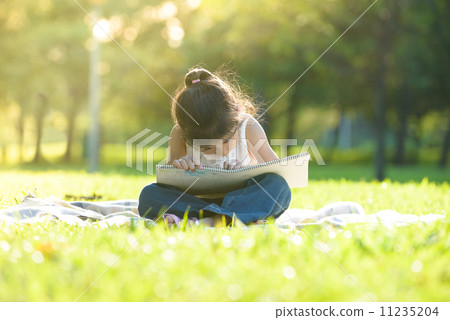Little girl in casual sitting on a mat drawing in a park 11235204