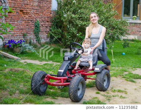 Little cute boy driving pedal car with young mother 11235862