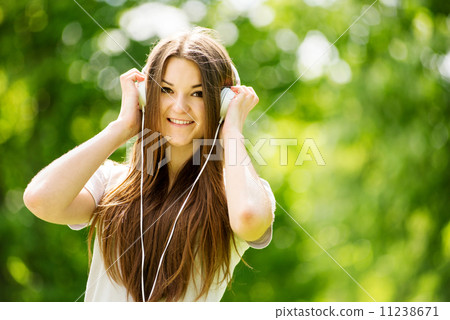 Beautiful young woman listening to music in a park 11238671