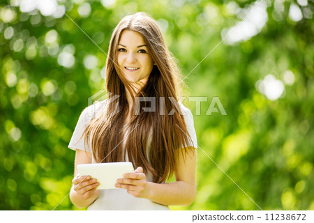 Beautiful young girl using a tablet in a park Beautiful young girl using a tablet in a park 11238672