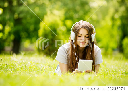 Young woman lying on the grass listening to music 11238674