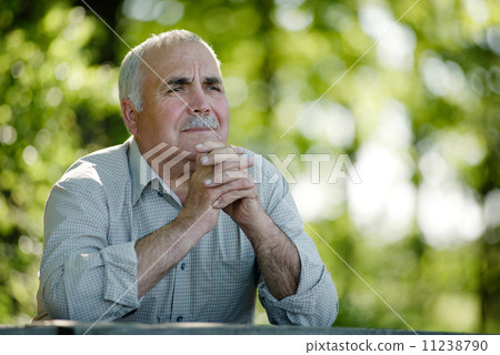 Elderly man sitting in the garden thinking 11238790