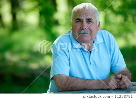Elderly man sitting outdoors smiling at the camera 11238791