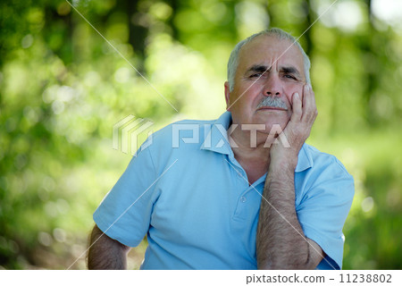 Elderly man sitting outdoors smiling at the camera 11238802