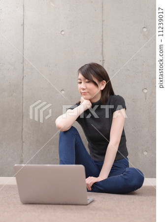 坐地板和使用膝上型計算機的一個少婦 11239017