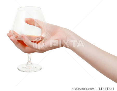 hand holds glass goblet with brandy 11241881