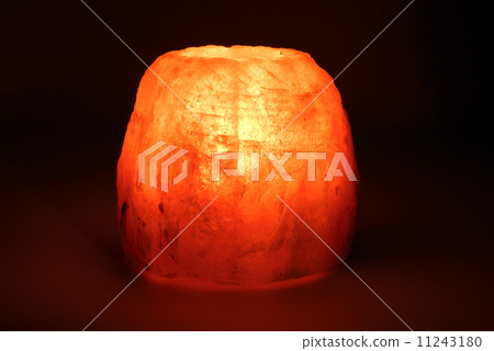 Burning candle placed in a candlestick made of a piece of salt 11243180