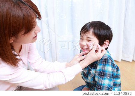 Mom placing an adhesive plaster on the face of a boy 11243883