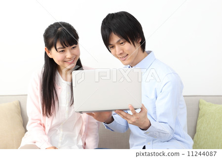 A young couple looking at a laptop (couples, men and women) 11244087
